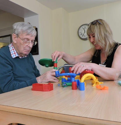 Plactic building shapes on table showing with Support Staff showing activities in Care Home