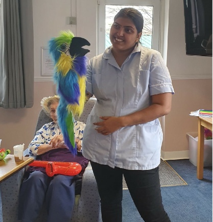 Member of Support Staff with arm puttet showing stimulating and fun activities in Care Home